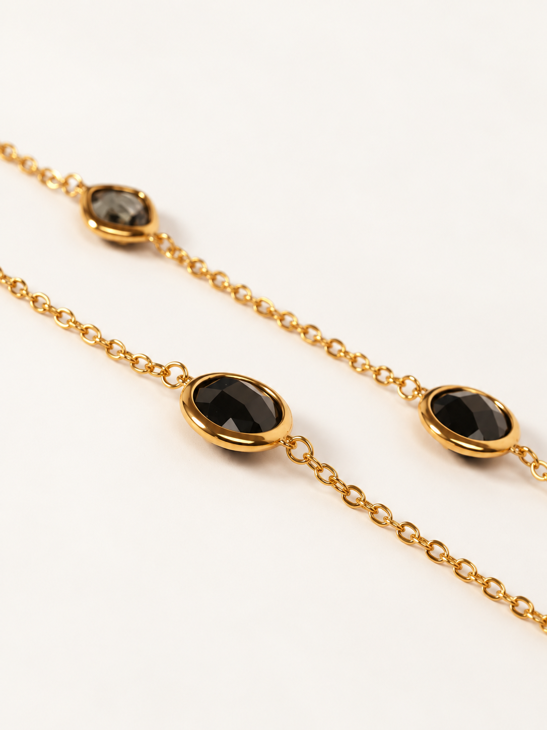 Collana Lunga Luce Nera - Finitura Dorata: dettaglio ingrandito su fondo chiaro